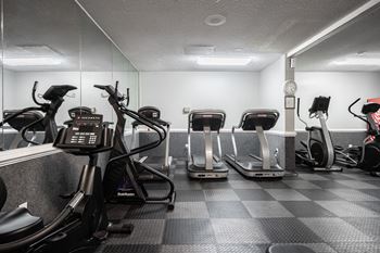 A gym with treadmills, elliptical machines, and a weight machine